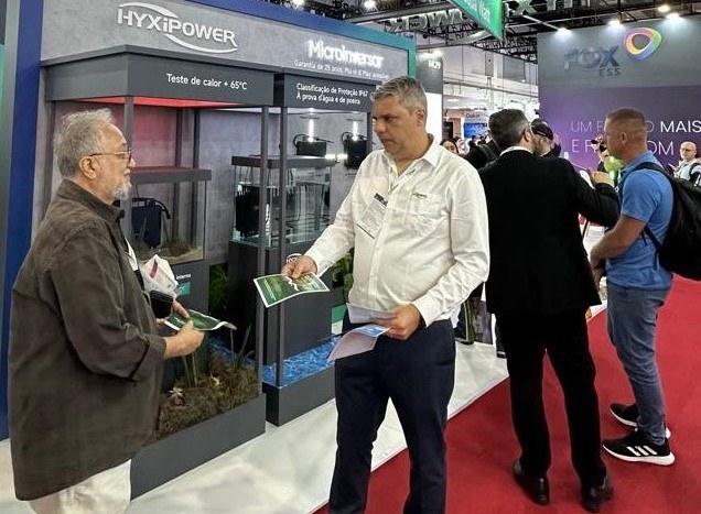 Foto mostra dois homens com papel na mão