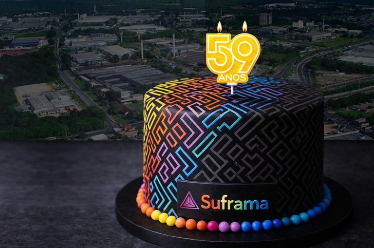 Foto mostra a arte de um bolo de aniversário fazendo referência a 59 anos e com uma imagem ao fundo de fábricas