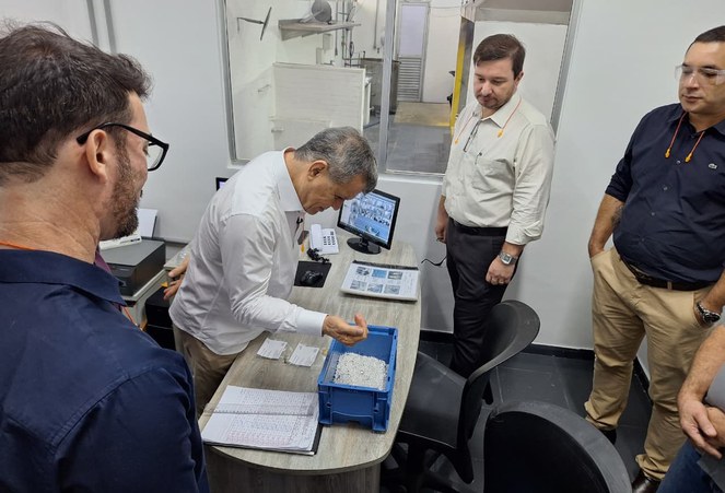 Foto mostra homem de blusa branca manuseando uma caixa com produtos