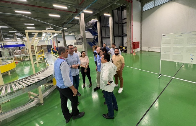 Foto mostra pessoas visitando uma linha de produção em uma fábrica