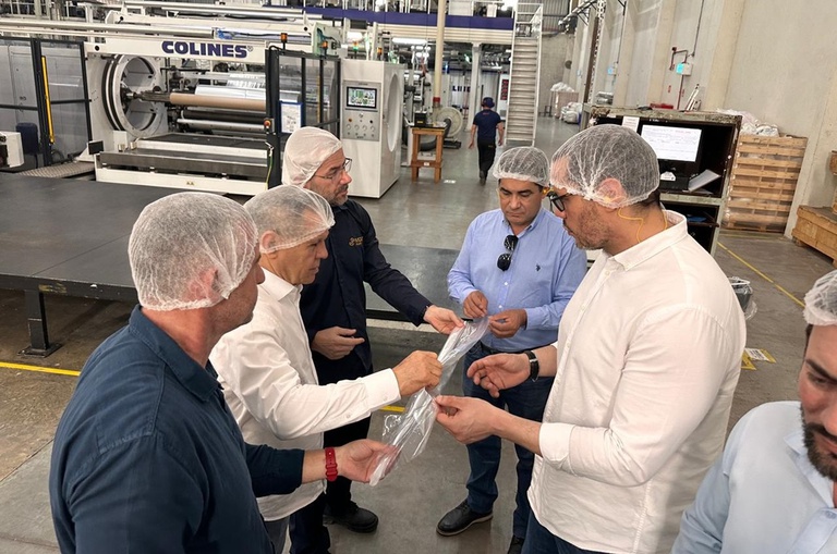 Foto mostra pessoas com touca mexendo em produto plástico