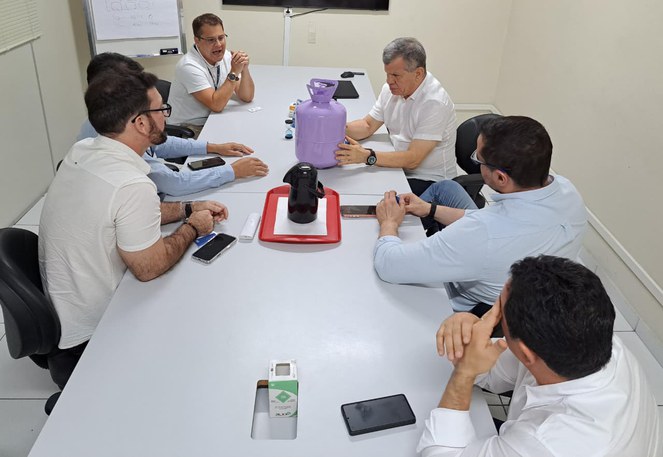 Foto mostra homens olhando para uma botija de gás lilás