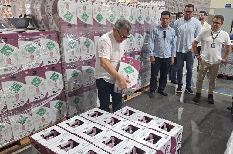 Foto mostra homem segurando uma caixa, observado por outros homens