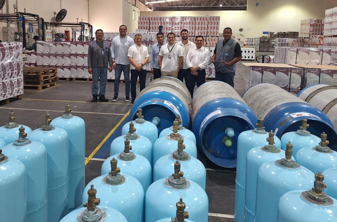 Foto mostra homens posando para sessão de fotos em meio a botijas de gás e caixas