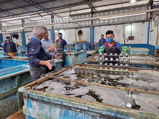 Foto mostra homens verificando uma produção de peças para veículos de duas rodas