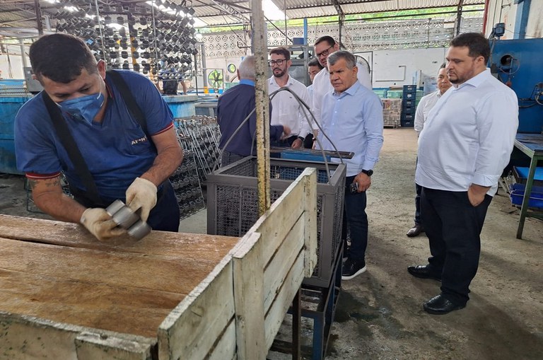 Foto mostra homens em visita a uma fábrica de peças para veículos de duas rodas