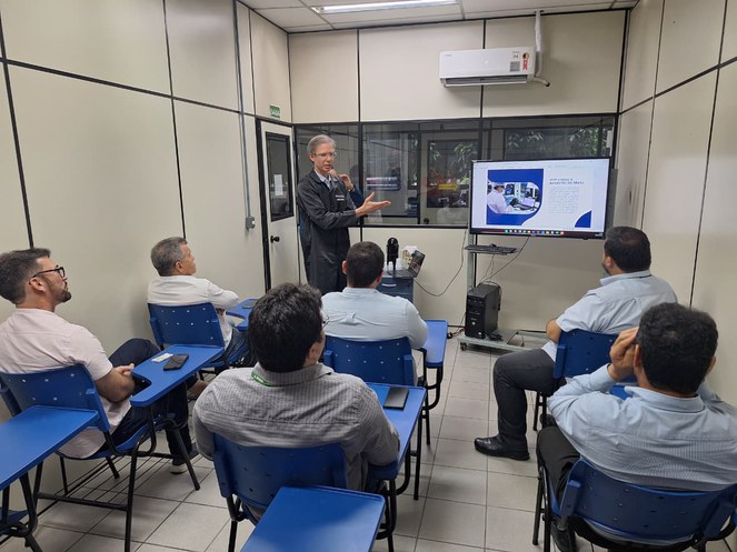 Foto mostra homem em pé fazendo uma explanação com o apoio de um telão