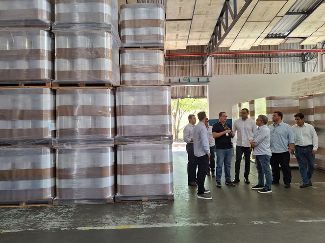 Foto mostra homens em volta de produtos plásticos