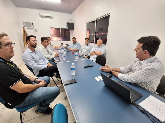 Foto mostra homens sentados à mesa em uma reunião