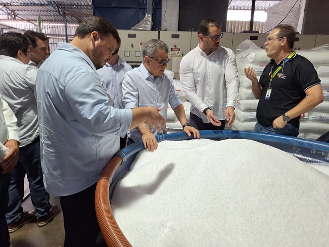 Foto mostra homens olhando para resíduos plásticos