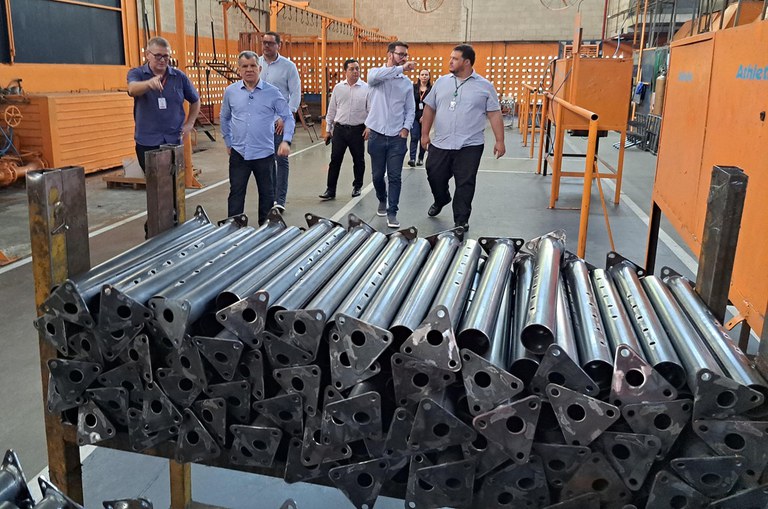 Foto mostra peças e um grupo de homens andando