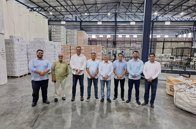 Foto mostra um grupo de pessoas posando para todo dentro de uma empresa de papel