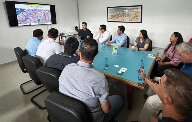 Foto mostra pessoas numa reunião olhando para um telão