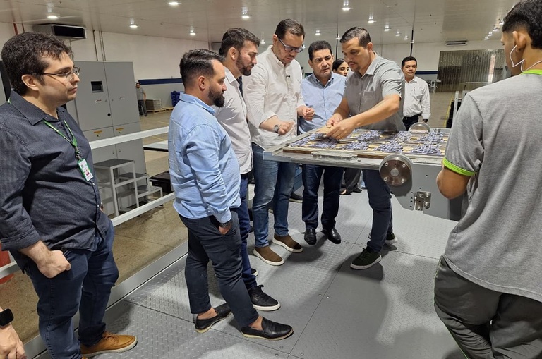 Foto mostra grupo de pessoas manuseando produtos de embalagens em uma fábrica