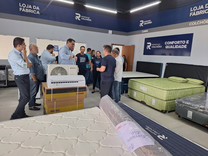 Foto mostra pessoas em um ambiente com colchões e ar-condicionado em demonstração