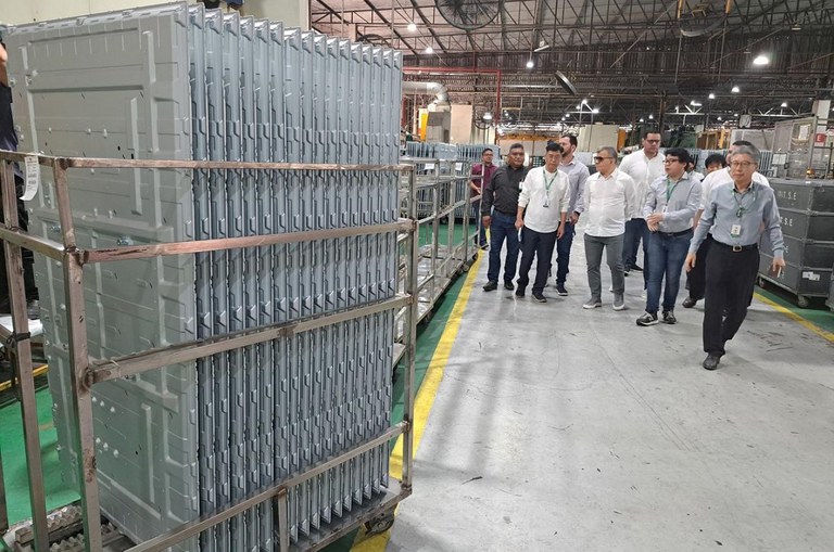 Foto mostra grupo de homens andando dentro de uma empresa