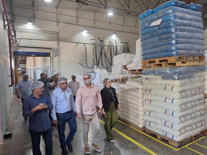 Foto mostra grupo de homens com toca branca na cabeça em uma visita a uma linha de produção de embalagem plástica