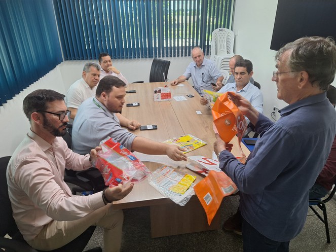 Foto mostra grupo de homens manuseando embalagens plásticas de alimentos