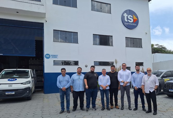 Foto mostra pessoas posando para foto em frente a um empreendimento industrial