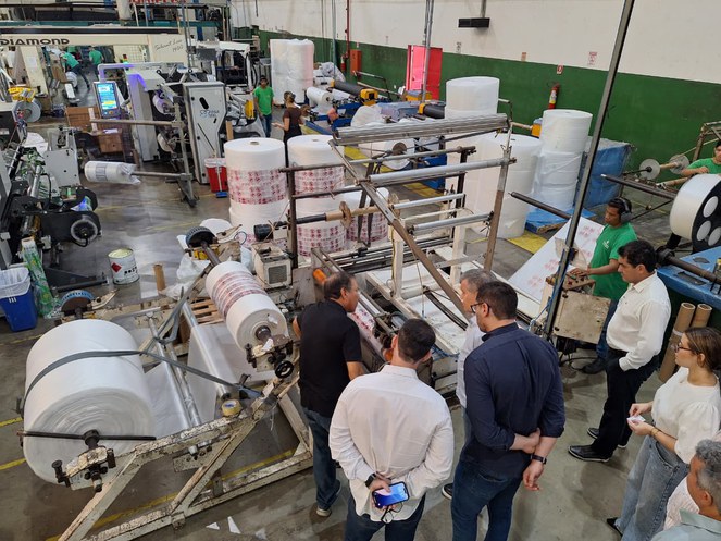 Foto mostra pessoas visitando uma fábrica de produtos de embalagens plásticas
