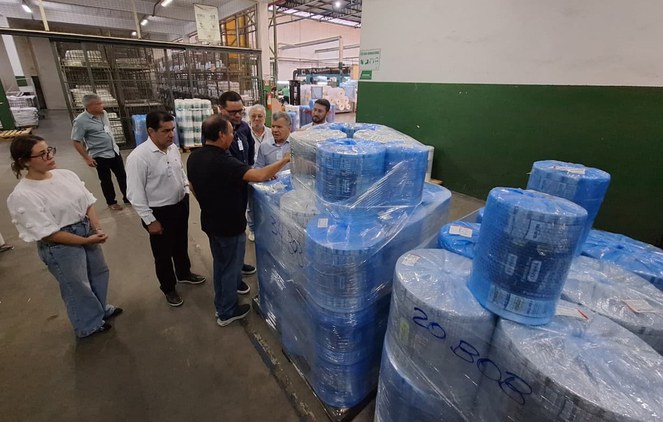 Foto mostra grupo de pessoas visitando uma fábrica de produtos de embalagens plásticas