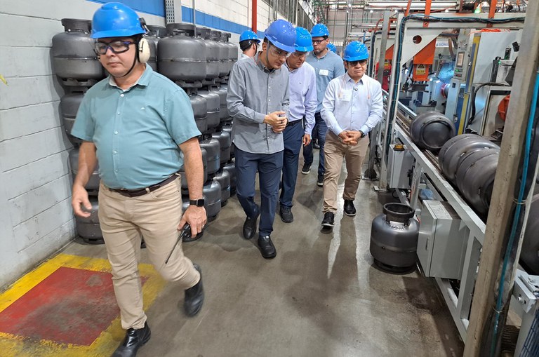 Foto mostra homens de capacete azul em uma fábrica de botijas de gás