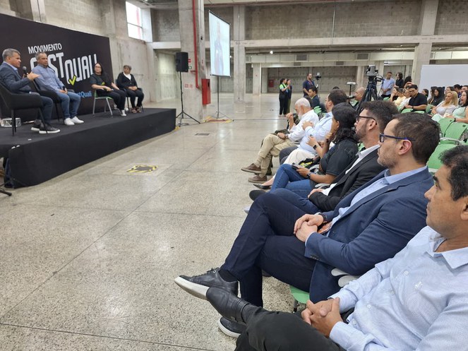 Foto mostra homem com microfone falando em evento