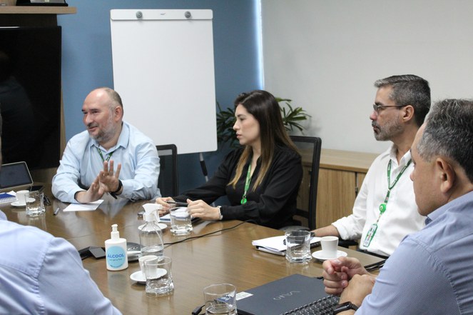 Foto mostra homem falando e gesticulando, observado por outras pessoas