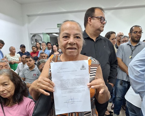 Foto mostra mulher segurando um documento