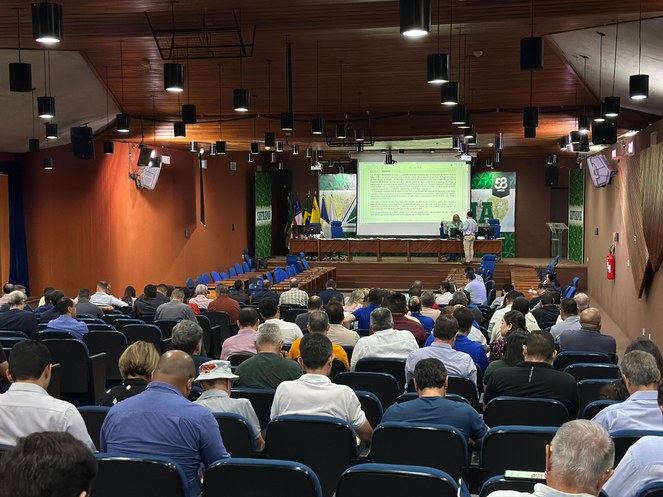 Foto mostra pessoas reunidas em um auditório para um evento
