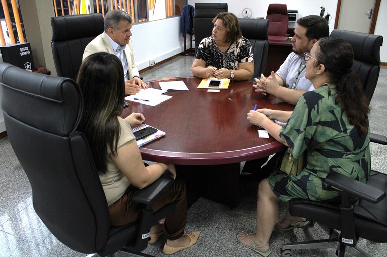 Foto mostra pessoas sentadas à mesa durante uma reunião de trabalho