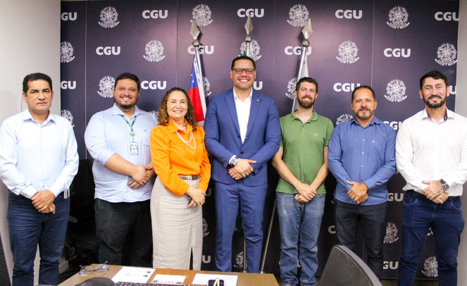 Foto mostra pessoas posando para uma sessão de foto com um painel grande ao fundo