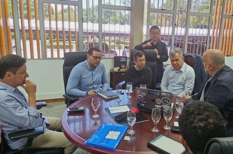 Foto mostra homens olhando para um notebook durante uma explanação