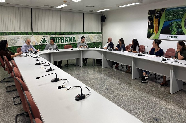 Foto mostra pessoas em volta de uma mesa numa reunião