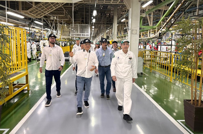 Foto mostra grupo de pessoas com boné caminhando dentro de uma empresa