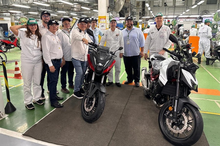 Foto mostra pessoas posando para foto em uma fábrica de motocicletas