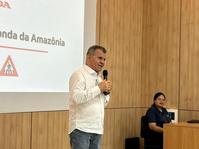 Foto mostra homem de camisa branca falando ao microfone