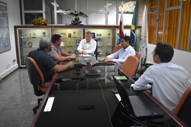 Foto mostra homem de blusa branca fazendo uma explicação a um grupo de outros quatro homens