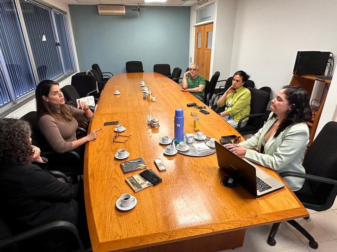Foto mostra pessoas sentadas numa reunião