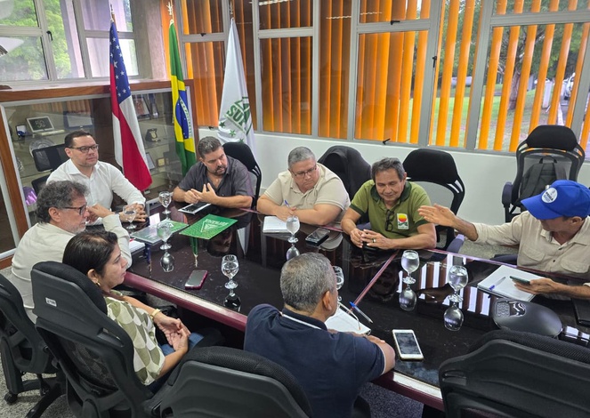 Foto mostra pessoas sentadas numa reunião