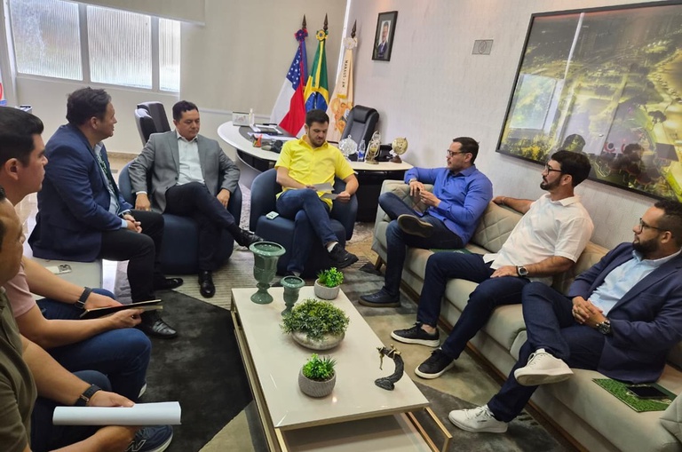 Foto mostra pessoas sentadas em uma reunião