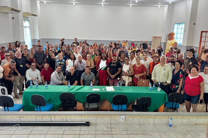 Foto mostra grupo de pessoas posando para foto num auditório