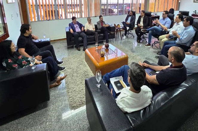 Foto mostra pessoas sentadas numa reunião