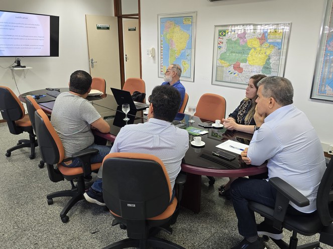 Foto mostra um grupo de pessoas olhando para um telão