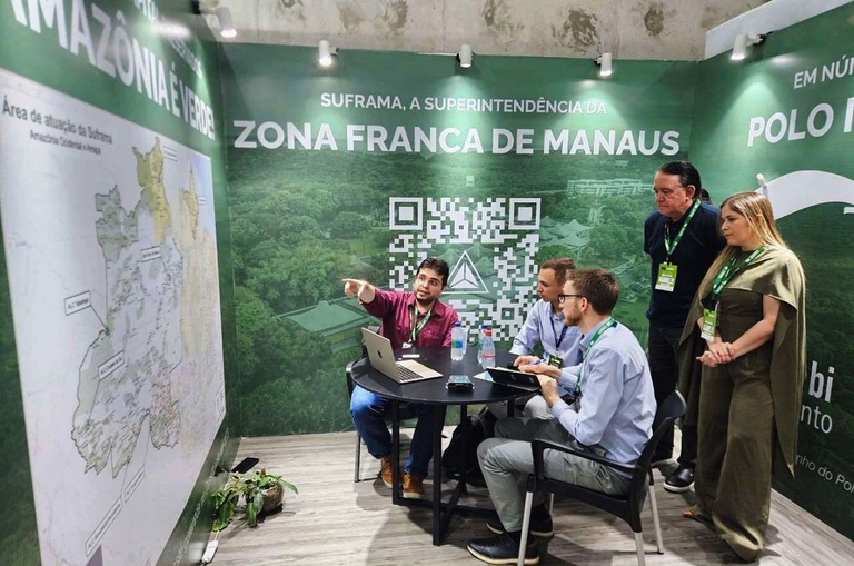 Foto mostra homem apontando para um mapa observado por outras pessoas