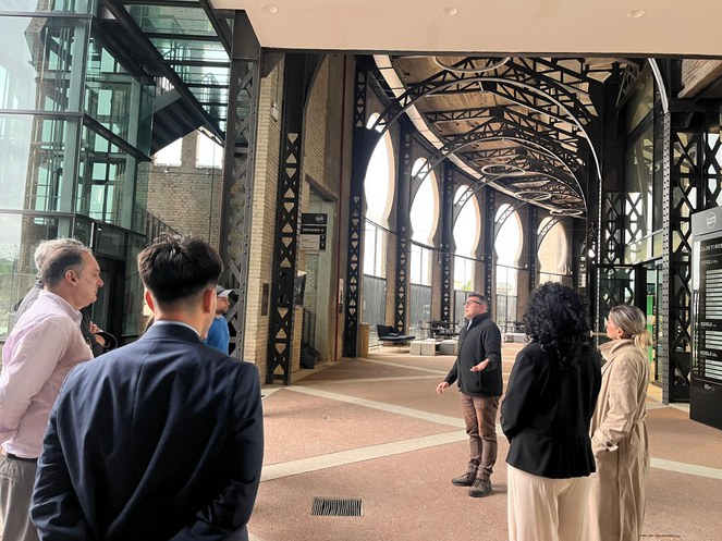 Foto mostra homem numa escada conversando com grupo de pessoas