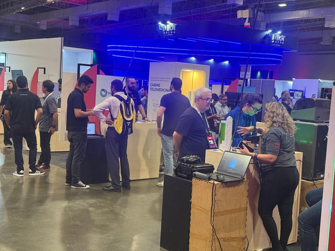 Foto mostra mulher de blusa cinza falando a um senhor de óculos