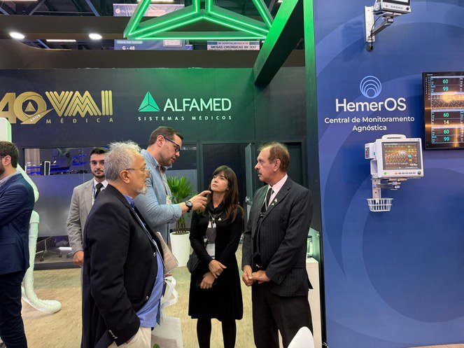 Foto mostra homem de óculos e blusa azul clara fazendo uma explicação para um casal