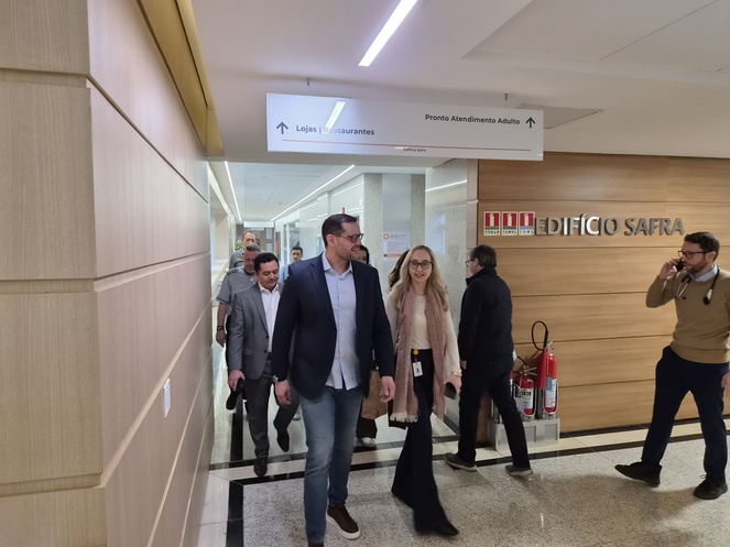 Foto mostra pessoas andando num ambiente fechado