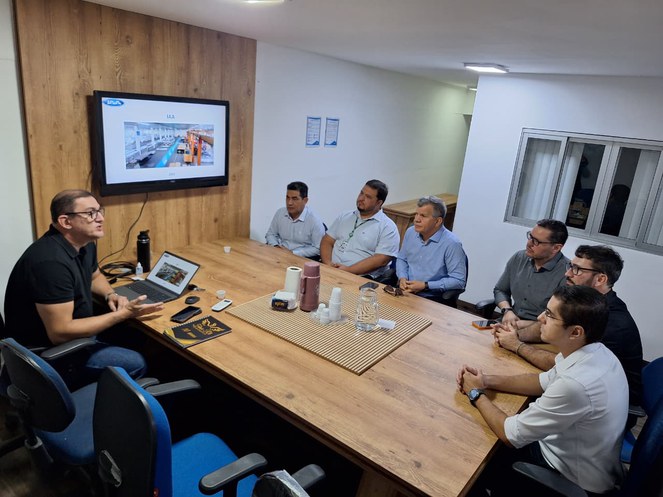 Foto mostra pessoas em reunião, com um telão como apoio